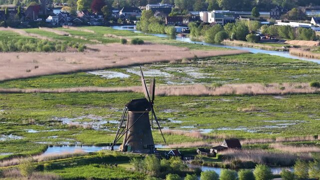 Traditional dutch windmill spinning in kinderdijk polder landscape