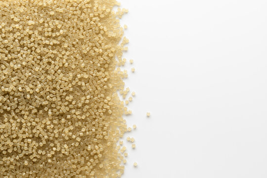 Translucent beige plastic pellets form dense textured border on white background for polymer industry and packaging concepts.