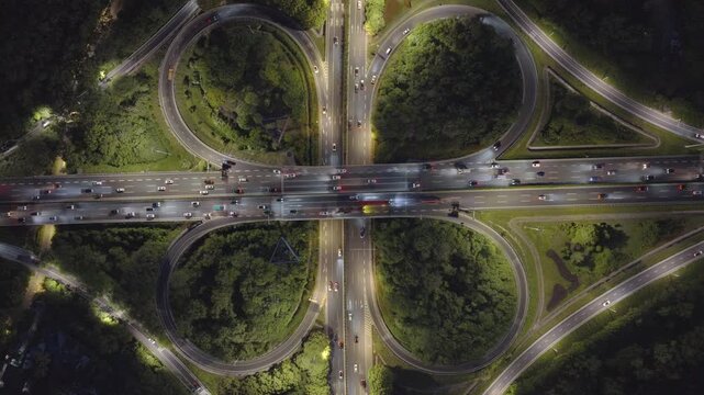 Aerial view of symmetrical highway interchange at night with vibrant light trails