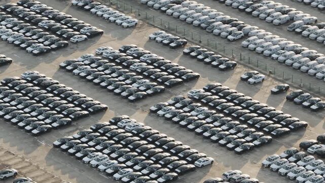Aerial view of dense car storage lot and elevated road at port logistics terminal