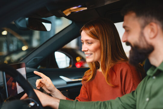 Couple exploring modern car infotainment system during dealership visit