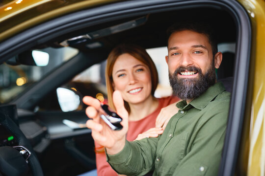 Man holding car keys after buying new vehicle at dealership