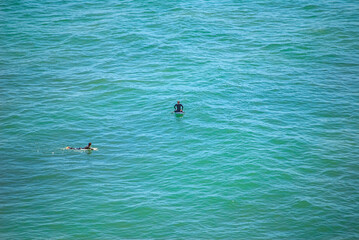 Fototapeta premium Praia de Magoito, Sintra,, Portugal: Two surfers on surfboards in blue ocean water