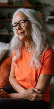 Older woman gazing thoughtfully while seated in living room