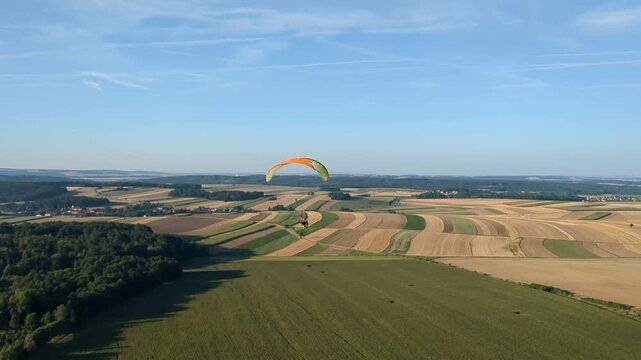 Motorized paragliding pilot flying low above ground enjoying powered flight adventure