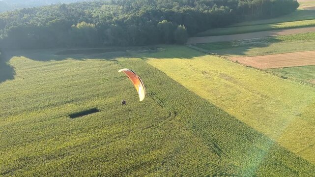 Motorized paragliding pilot flying low above ground enjoying powered flight adventure