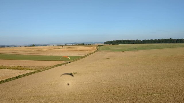 Motorized paragliding pilot flying low above ground enjoying powered flight adventure