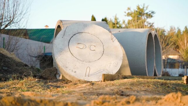 Concrete septic tank rings and cover on construction site before installation. Precast concrete well rings for sewage system in countryside
