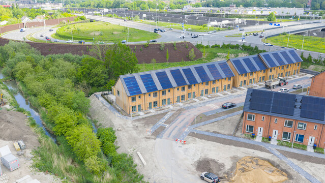 Aerial view of modern wooden houses with solar panels on roofs near a highway and green trees in Utrecht, Utrecht, Netherlands.