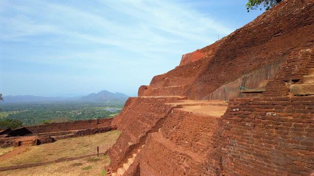 Jib up from ruins of Sigiriya Rock Fortress revealing lone tree, nature retaking bricks