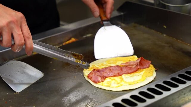 Street vendor preparing Dan Bing, a traditional Taiwanese breakfast, on a hot griddle at a night market