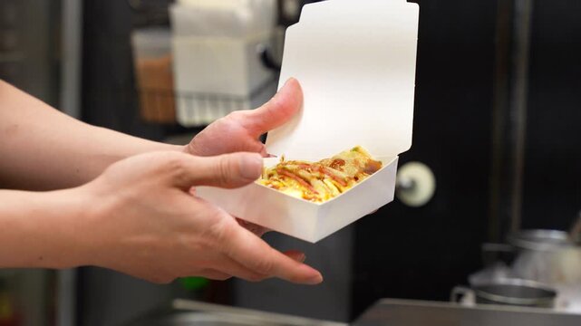 Street food vendor is pouring sauce on a Taiwanese egg pancake, Dan Bing, at a night market