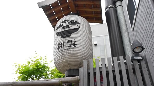 Traditional white paper lantern, or chochin, with Japanese calligraphy outside a seafood restaurant