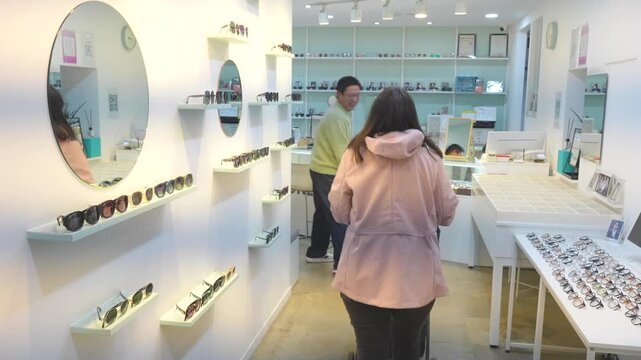 Cheerful male eye doctor welcoming a female patient entering his modern eyewear shop