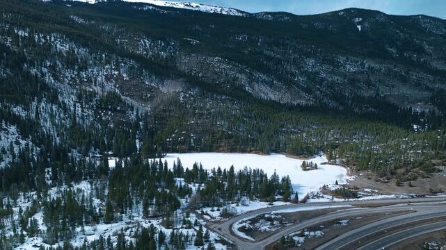Frisco Gulch wide valley with forest and snow patches beneath cloudy sky, aerial drone overview