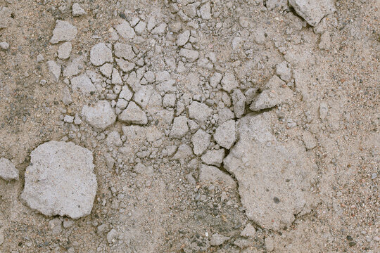 Close-up of cracked, fragmented concrete reveals the silent story of decay and endurance. The rough, uneven surface speaks of years of exposure, stress, and the relentless force of nature reclaiming m