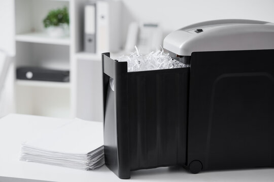 Modern shredder with documents on desk in office, closeup