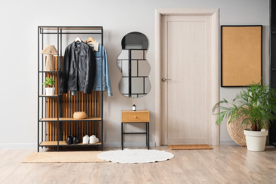 Interior of stylish hallway with mirror, table and coat rack