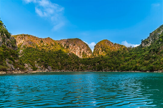 A view from a sampan in an internal bay accessed from a water eroded tunnel through Karst limestone cliffs in Ha Long Bay, Vietnam in late afternoon