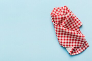 Obraz premium Red and white checkered tablecloth crumpled on light blue background