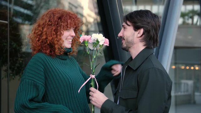 Affectionate man surprises his girlfriend with a bouquet of carnations during a romantic date
