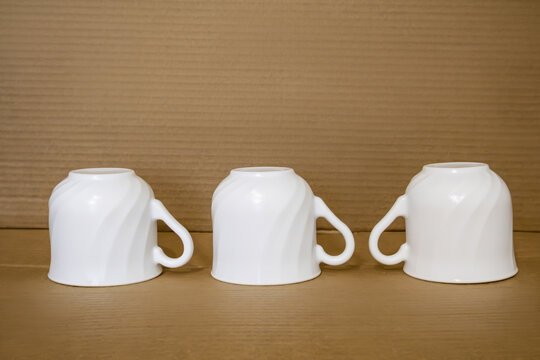 Minimalistic still life evokes a sense of pause, anticipation. Clean white mugs, turned upside down, rest on warm wooden surface - a quiet moment before a shared cup of tea or coffee.