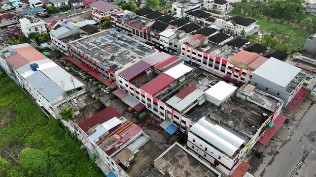 An aerial view showing a row of buildings and rooftops facing a narrow street, along with parked cars.
