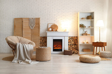 Naklejka premium Interior of living room with armchair, shelving unit, folding screen, coffee table and firewood near fireplace