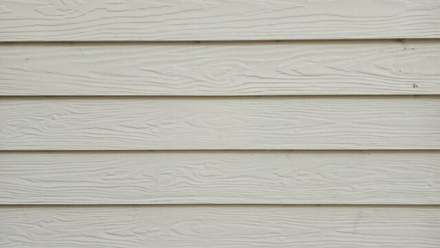 Cream lap siding wall texture. Cream-colored lap siding wall texture with natural wood grain. Horizontal synthetic wood grain siding.