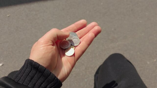 Hand counting British coins in natural sunlight from first person perspective. Personal finance, budgeting, small change money concept with UK currency held outdoors. Everyday expenses, savings