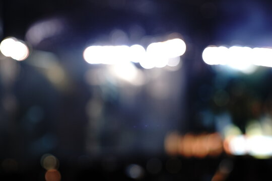 Abstract blurred concert or event lights with vibrant red, white, and warm tones, featuring defocused bokeh and dynamic light beams creating a dramatic night atmosphere.