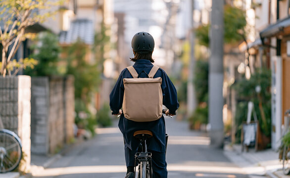 Man with a backpack riding a bicycle in a Japanese residential street