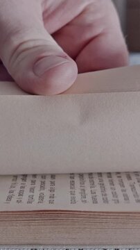 Closeup person flipping book pages rapidly while reading educational literature indoors vertically