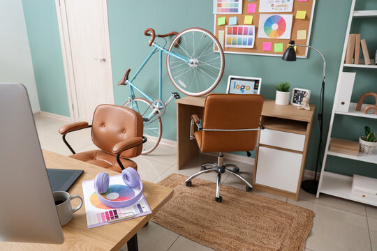 Interior of graphic designer's office with desks and bicycle
