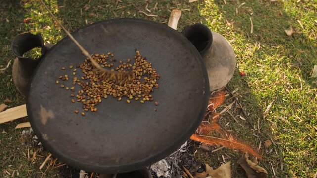 Une femme fait cuire des grains de caf&eacute; dans une casserole au-dessus d&rsquo;un feu ext&eacute;rieur, en &Eacute;thiopie