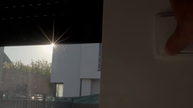 View from inside on automatic roller shutter rising on residential window with bright sunlight. Home security privacy control sun protection window covering and home automation concepts
