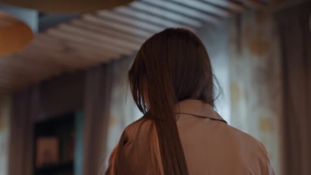 Woman in warm restaurant interior, coatclad guest moving through dimly lit dining room, closeup backshots and shoulder details, slow turn toward window, wood paneling, soft curtains, glassware