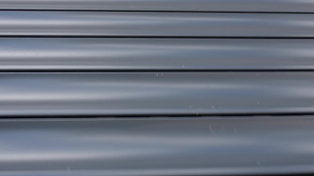 Exterior automatic roller shutter closes over window glass. Home security privacy and smart home automation
