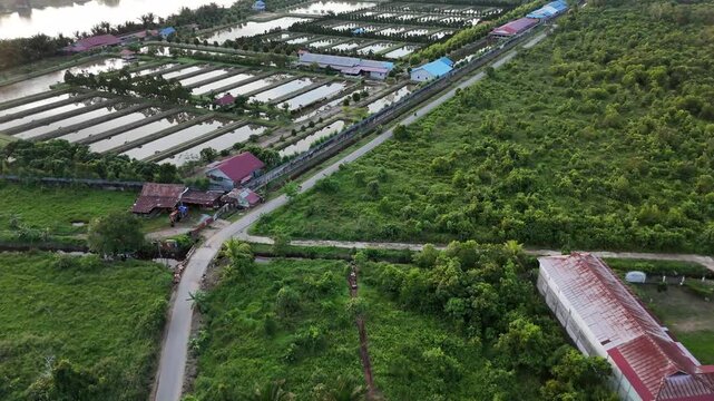 A view from above of fish farms and the countryside, with roads and green fields in Indonesia.