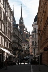 Fototapeta premium Scenic narrow street view leading to the majestic Cathedral of St. Peter and Paul in Brno, Czech Republic. European old town architecture with gothic spires against a soft sky