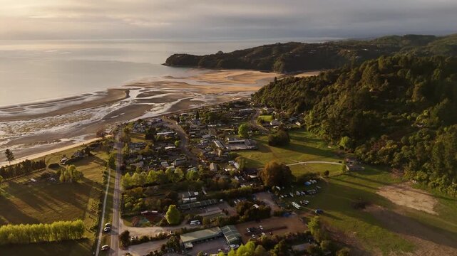 Coastal village of Marahau and its tidal flats during golden hour sunrise in New Zealand. Aerial drone