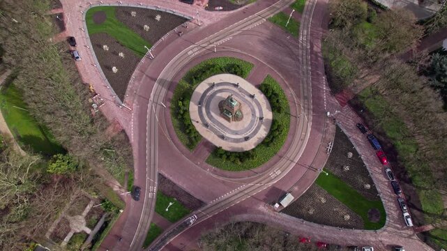 Top down aerial in Dutch capital The Hague, The Netherlands with lush greenery park around historic monument forming the center of an intersection crossroad
