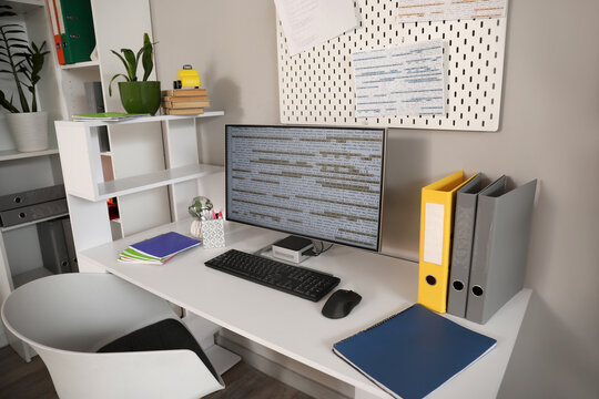 Programmer's desk with computer monitor and folders in office