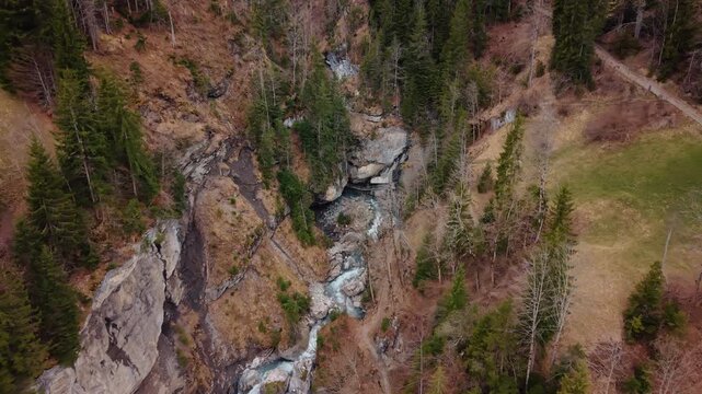 Aerial: pull out drone shot of river near Pochtenkessel deep rock funnel during the day near Adelboden, canton of Bern, Switzerland