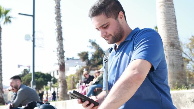 Man in blue summer outfit using smartphone on a sunny beach