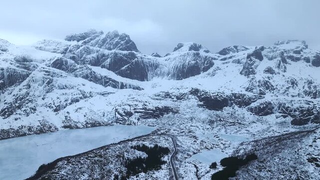 Stortvatnet on Austvagoya in Vagan Nordland Norway lies in glacial valley below Vagekallen massif with sharp ridges cirques and road linking Henningsvaer to E10 corridor drone parallax orbit clockwise