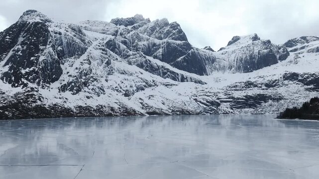 Stortvatnet lake on Austvagoya in Vagan Nordland Norway lies below jagged peaks including Vagekallen massif shaped by glacial erosion with cirques and ridges, drone pullback