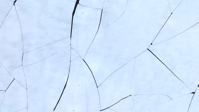 Stortvatnet lake on Austvagoya in Vagan Nordland Norway reveals thermal contraction cracks forming polygonal ice pattern with subtle surface reflection as drone rises from macro to close view