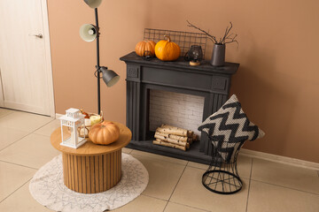 Naklejka premium Black fireplace, coffee table, pillow and pumpkins in autumn living room