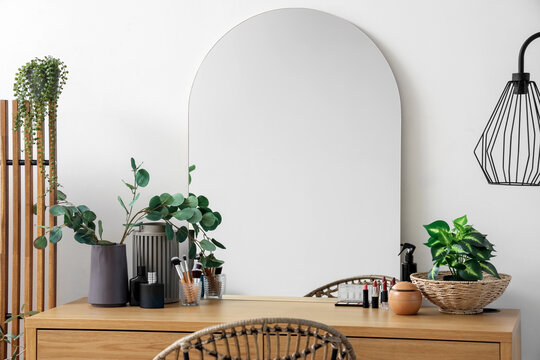 Makeup products with plants and mirror on table in dressing room